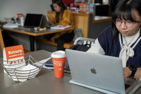 Student working with an orange cup reading "return me"