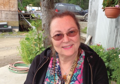 Amy L. Sandridge seated in front of the Wood River Market, smiling and wearing a black jacket.