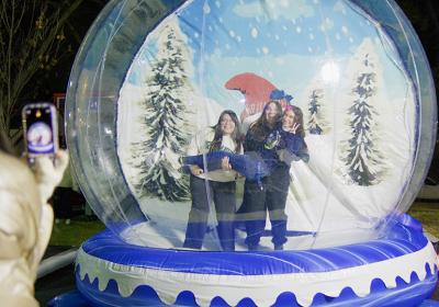 Three students taking a photo in an inflatable snow globe.