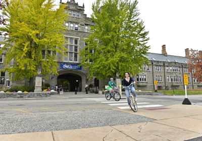 Students riding bicycles in front of Pem Arch