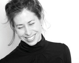 Black and white portrait of Amy Neswald, smiling with closed eyes.