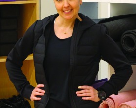 Portrait of Courtney Morris in front of a shelf full of yoga mats