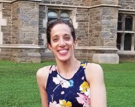 Marissa Patterson sitting on a short stone wall in a floral dress