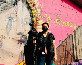 Tania Romero at Las Patronas, in front of a wall mural