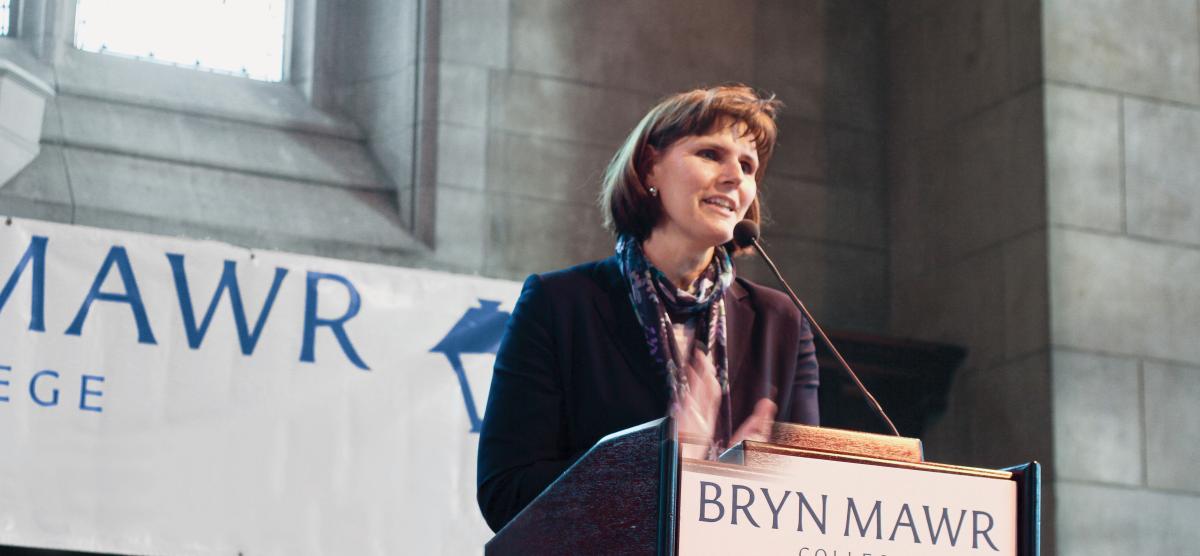 Kim Cassidy standing behind a podium with a Bryn Mawr banner in the background