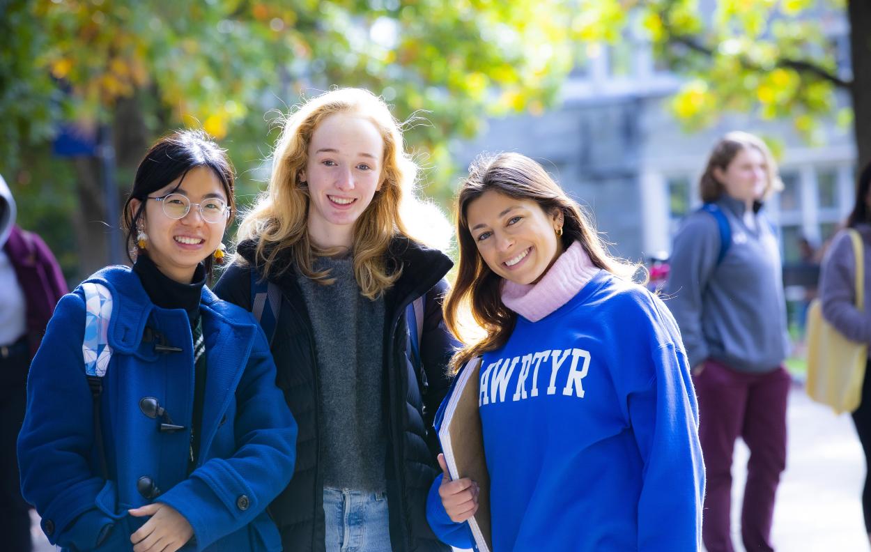 three students smiling in front of Pembroke Arch