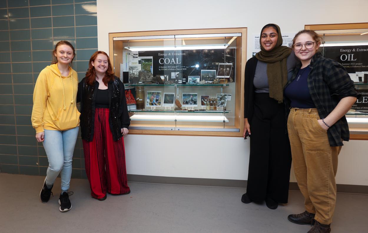 STEMLA Fellows post in front of display case