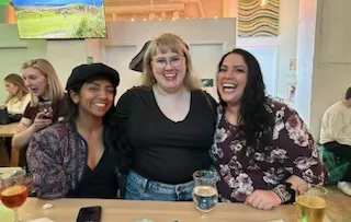 Three Mawrters smile together in a bar.