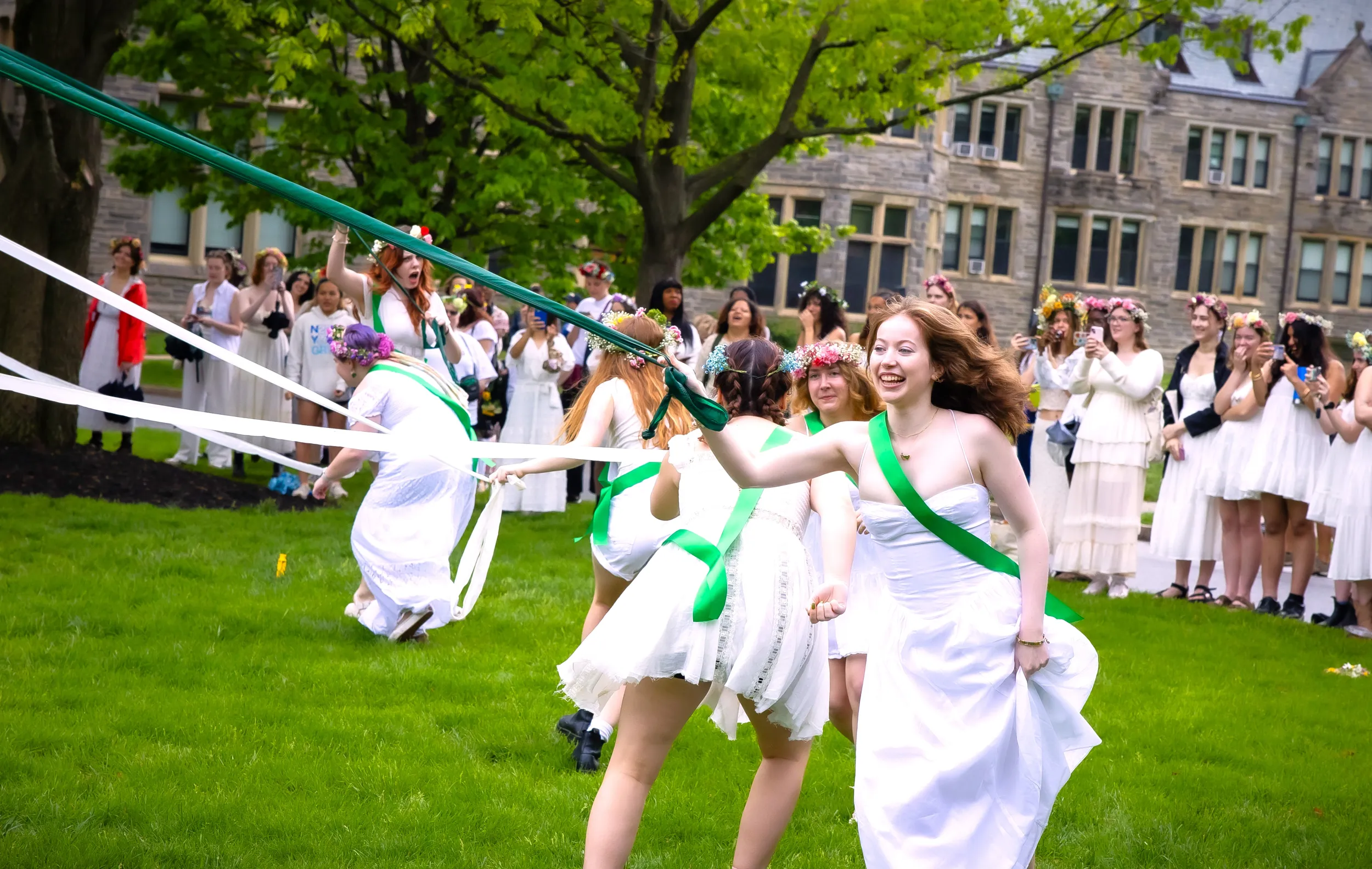 students participating in college traditions by running around the mayday pole