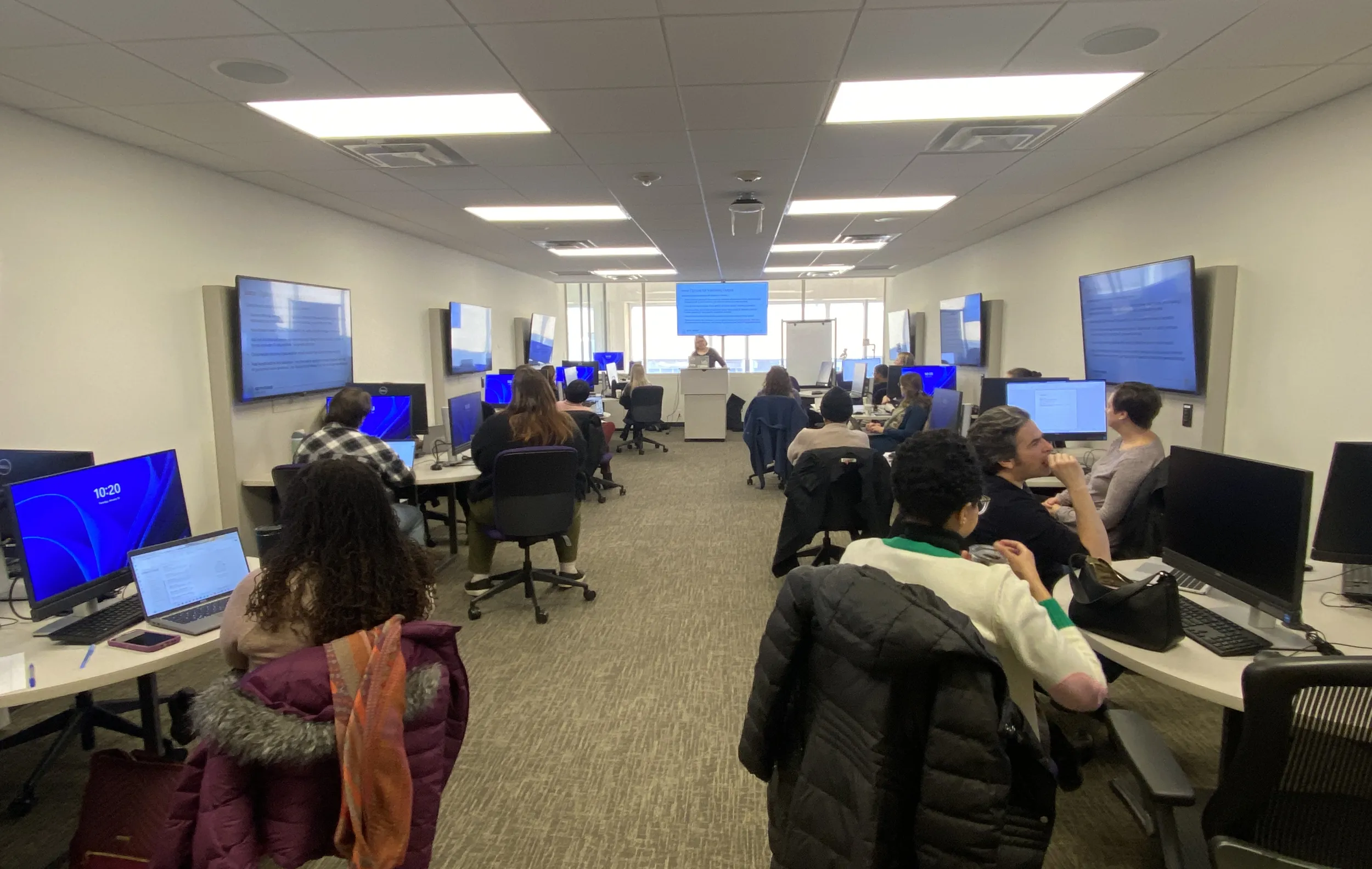 Participants sit in a computer lab, looking to the front where Jennifer Spohrer is speaking