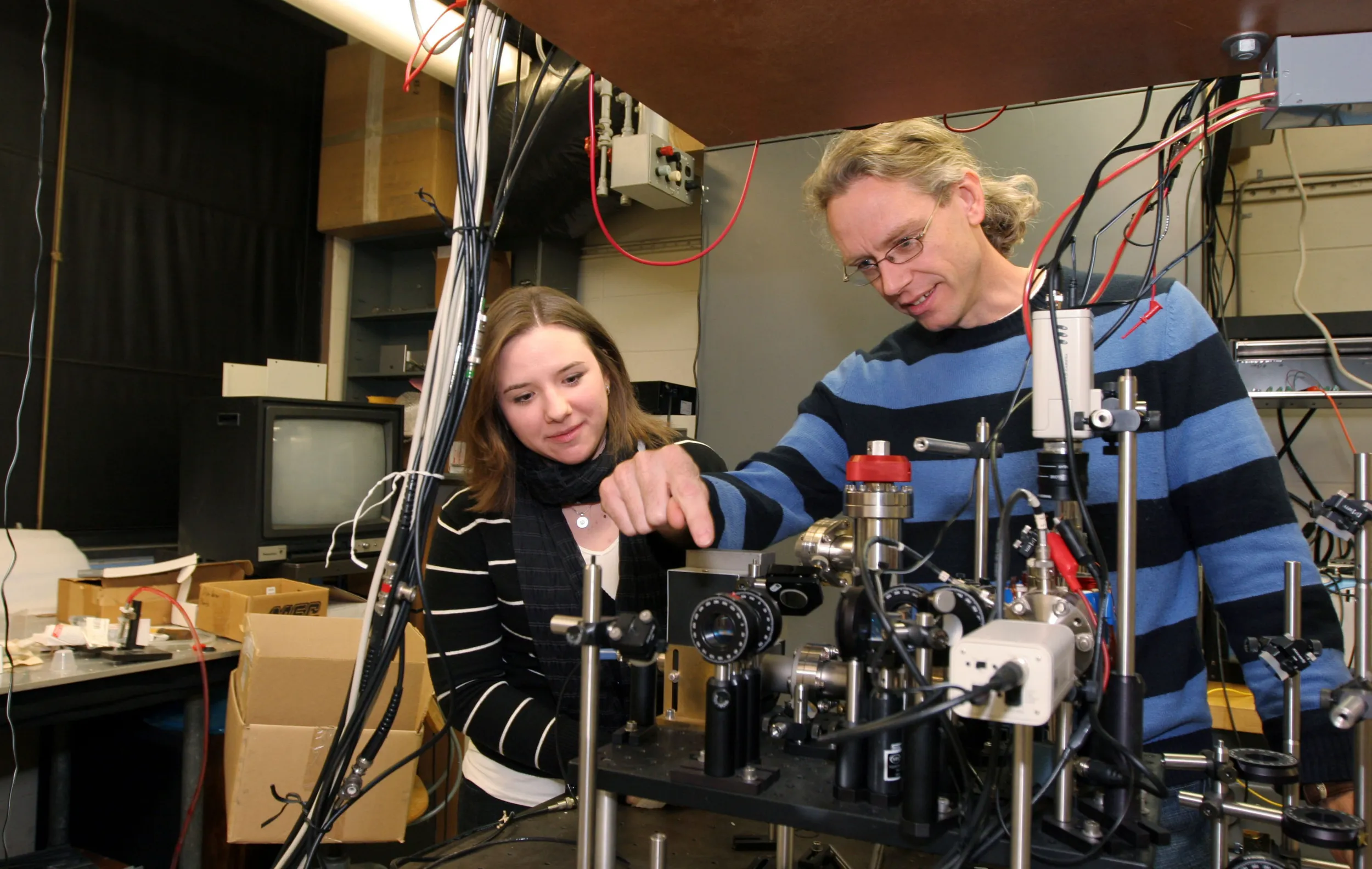 A professor and a student work on a piece of equipment                     