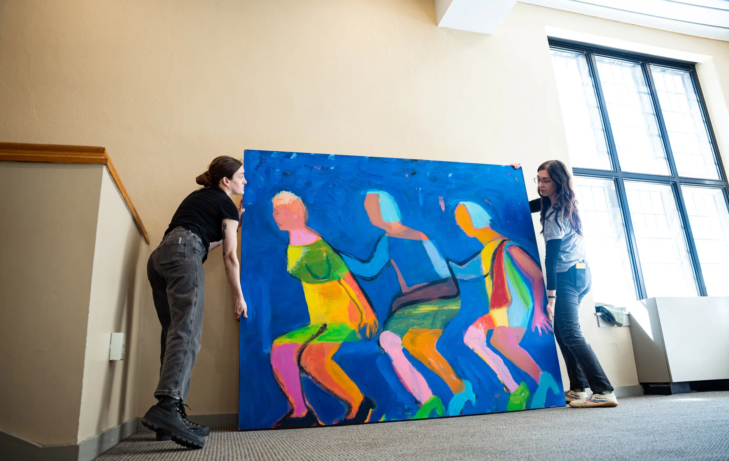 History of art students work on installing a painting by Katherine Bradford