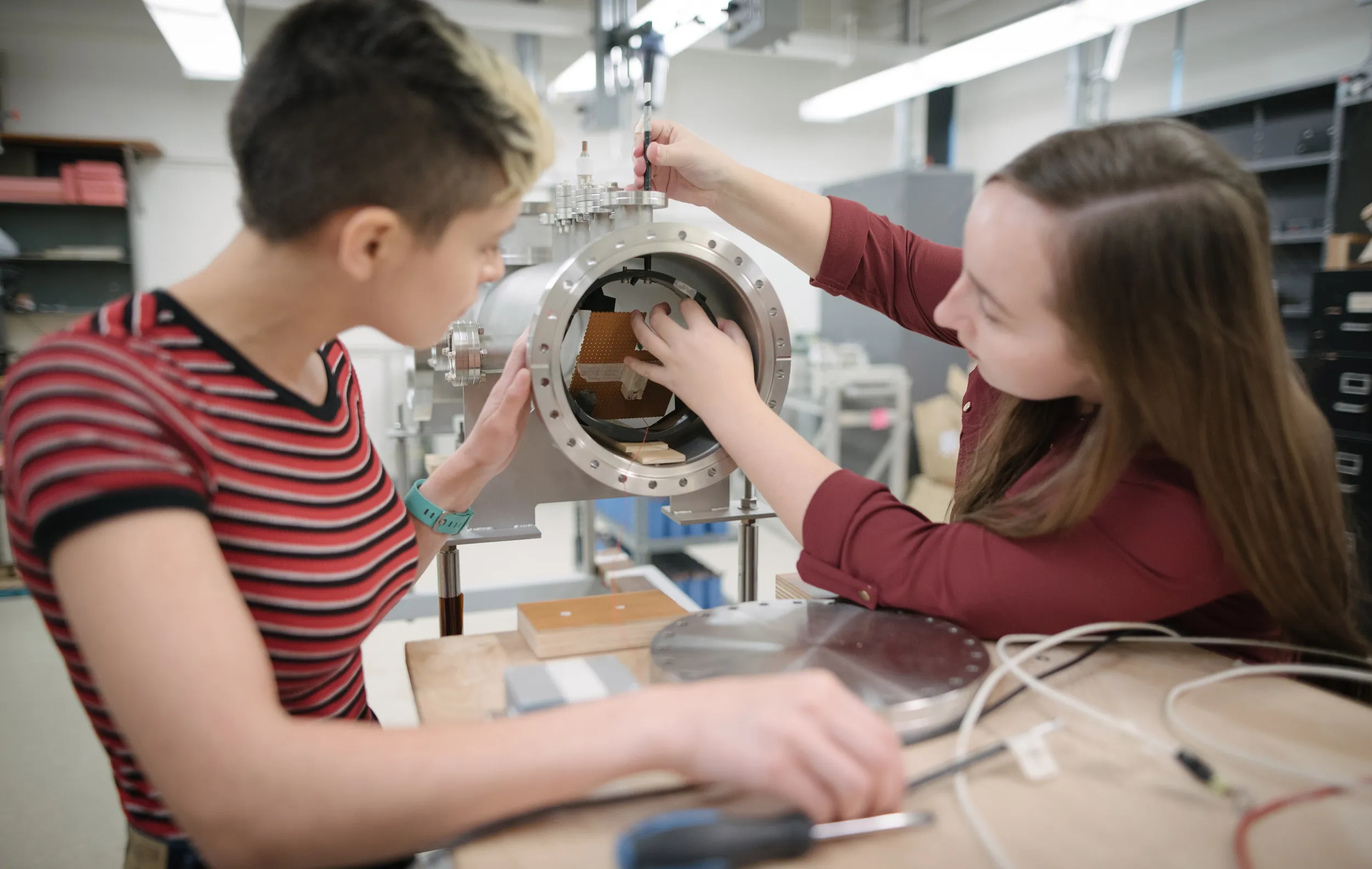 Two Physics students work on plasma lab equipment