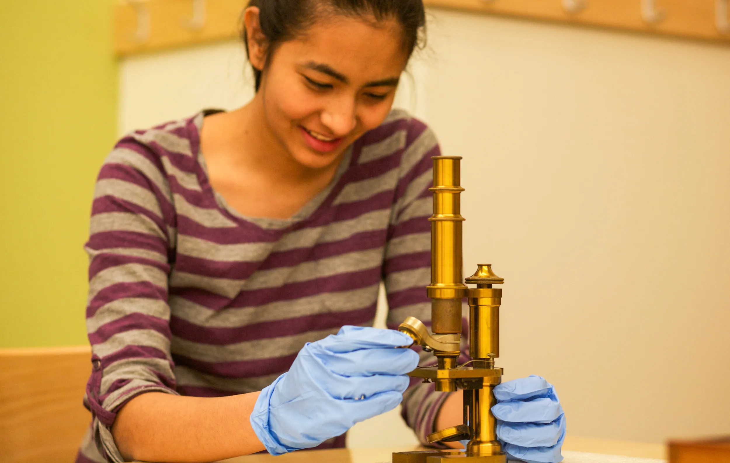Bryn Mawr history of art student examines a microscope in special collections