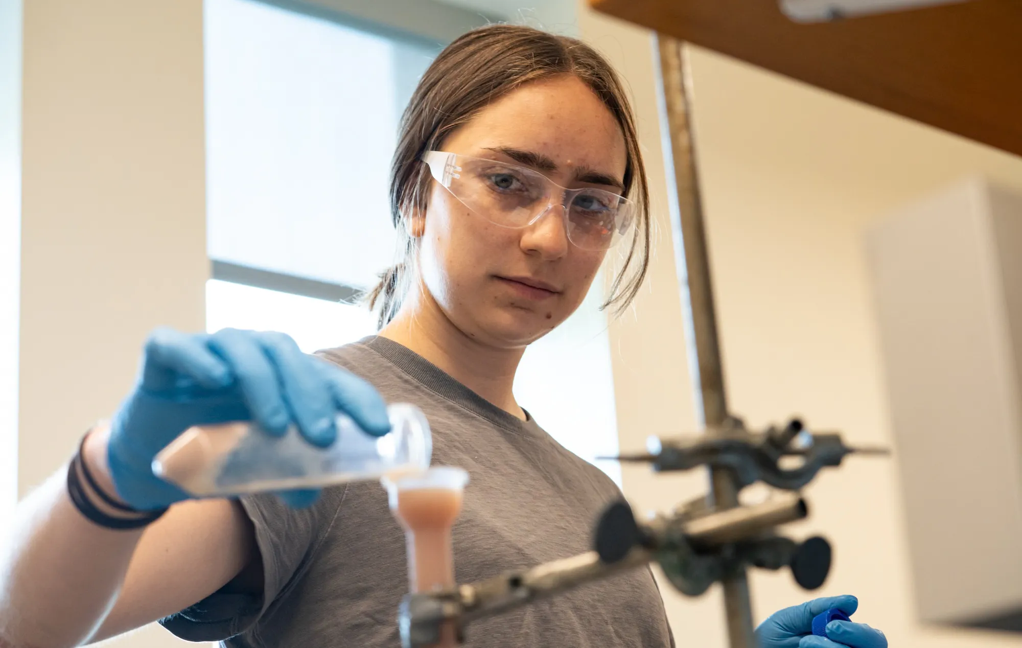 A Bryn Mawr Bachelors of Chemistry student pouring a substance in the Plummer lab