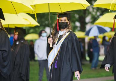 Students walk to graduation with yellow umbrellas