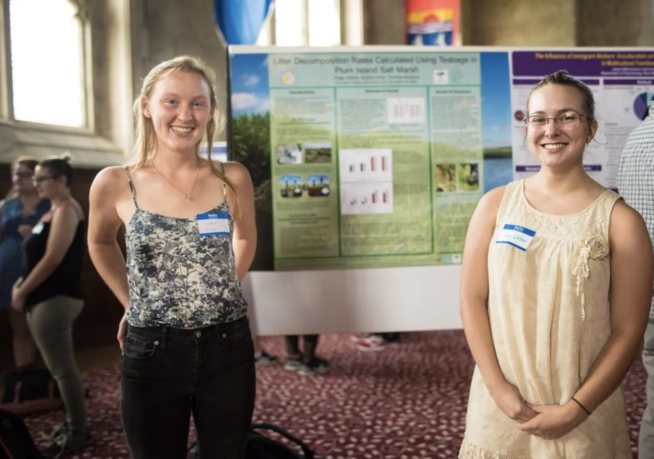 Two students smiling in front of a research poster in the Great Hall
