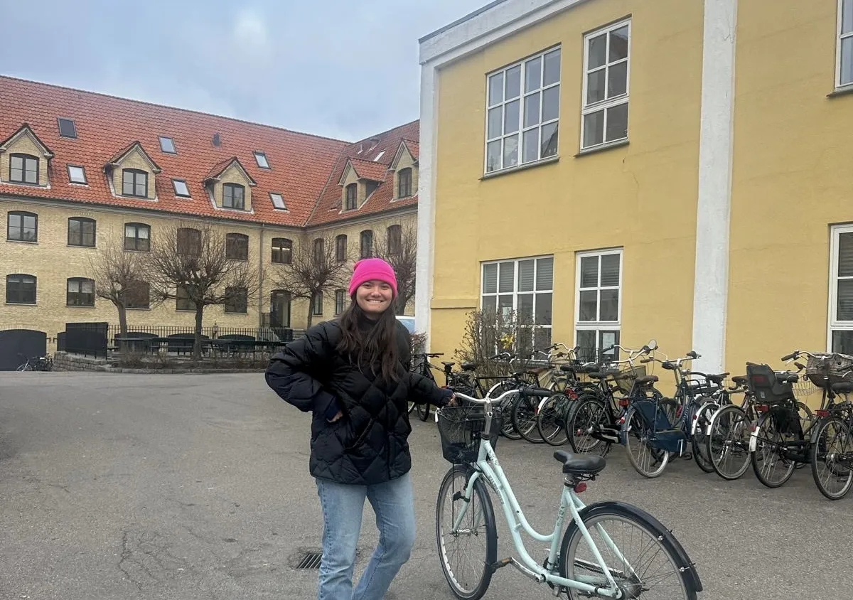 Sara standing in a courtyard next to a turquoise bike