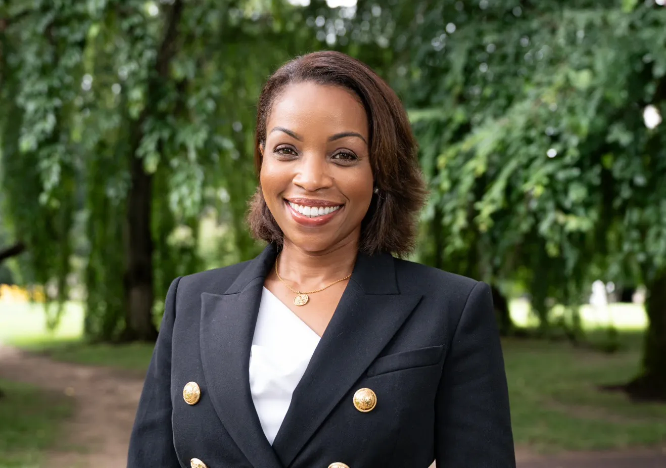 Woman in black blazer in front of trees
