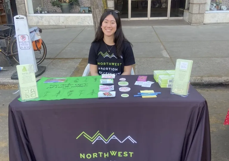 Leila working at a booth promoting access to reproductive healthcare