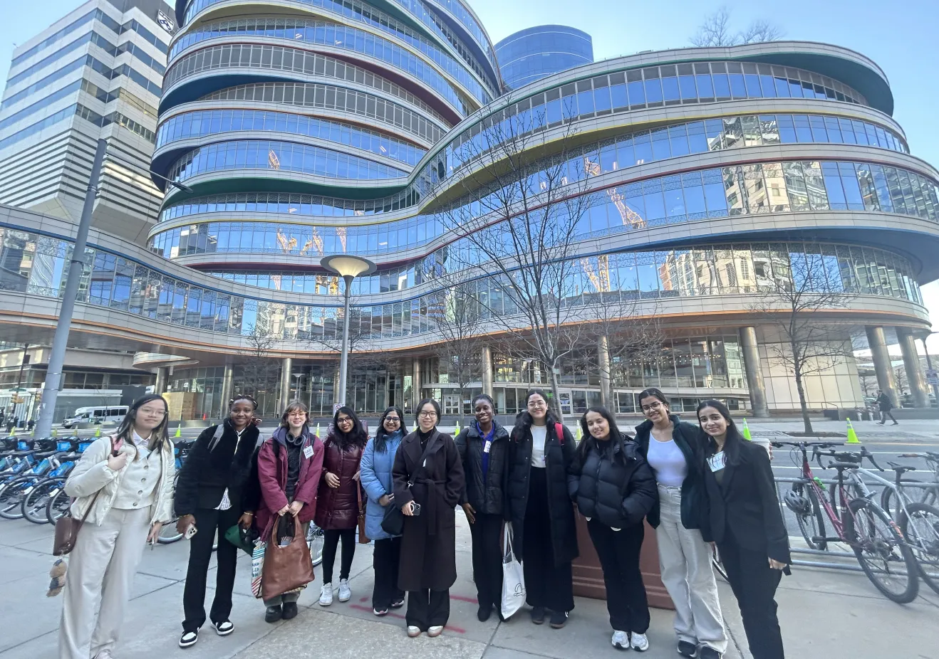 A group of students stand in front of a futuristic, curvy office building.