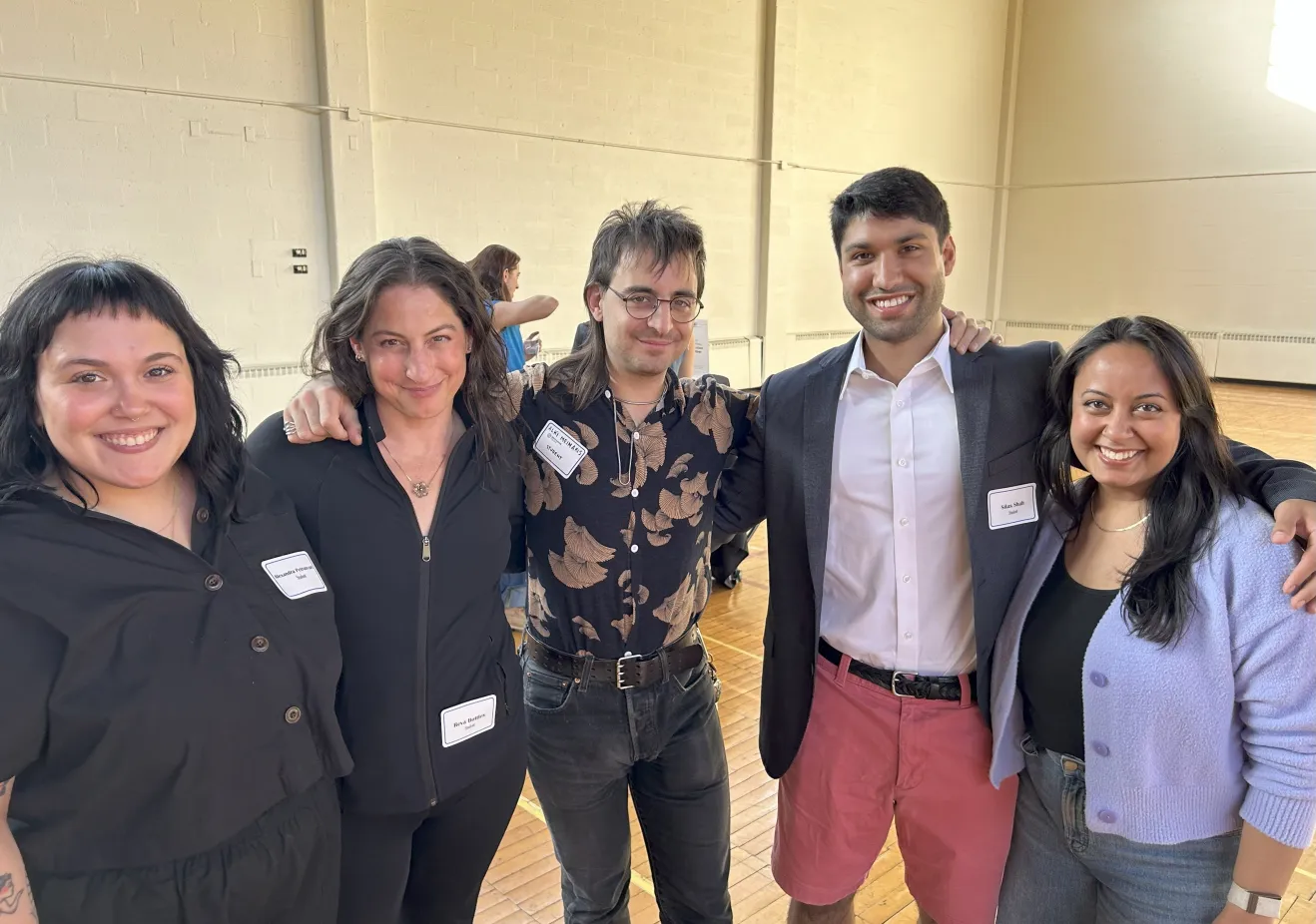 A group of five people smile at the camera.