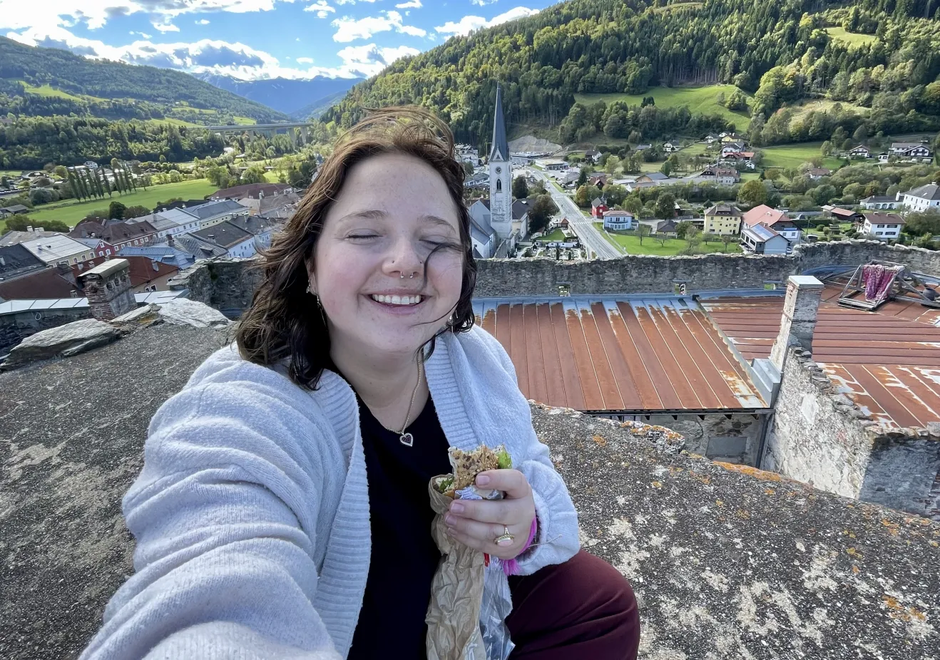 Katie sitting with a snack on a roof in Austria