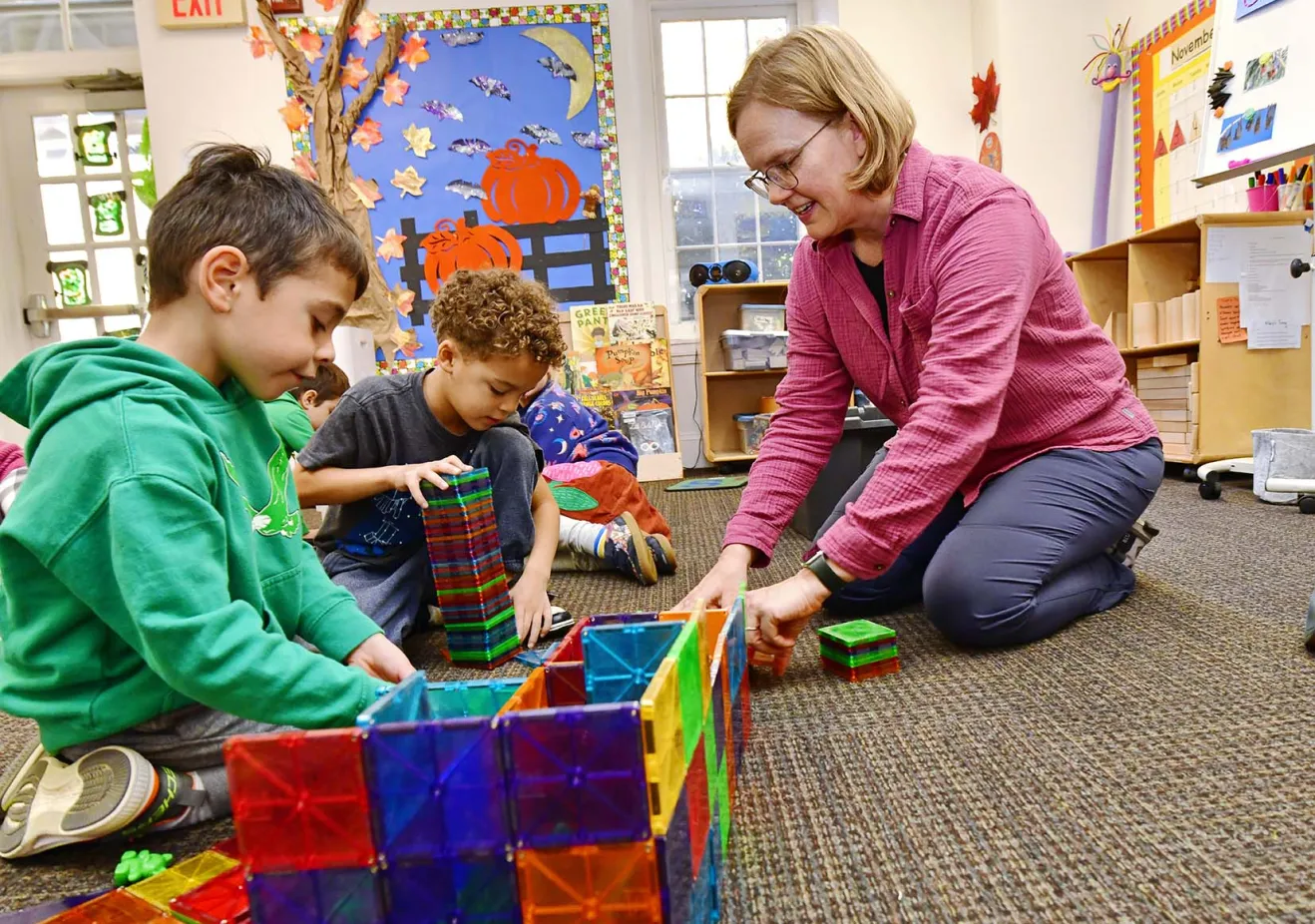 Students on floor playing with teacher