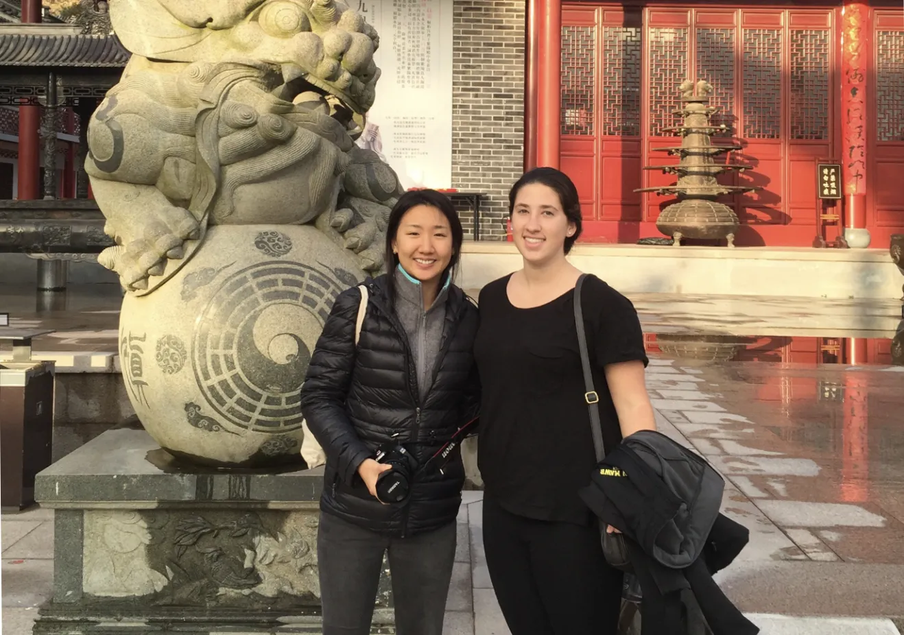 A Bryn Mawr College student studying abroad in China poses in front of a temple with a friend