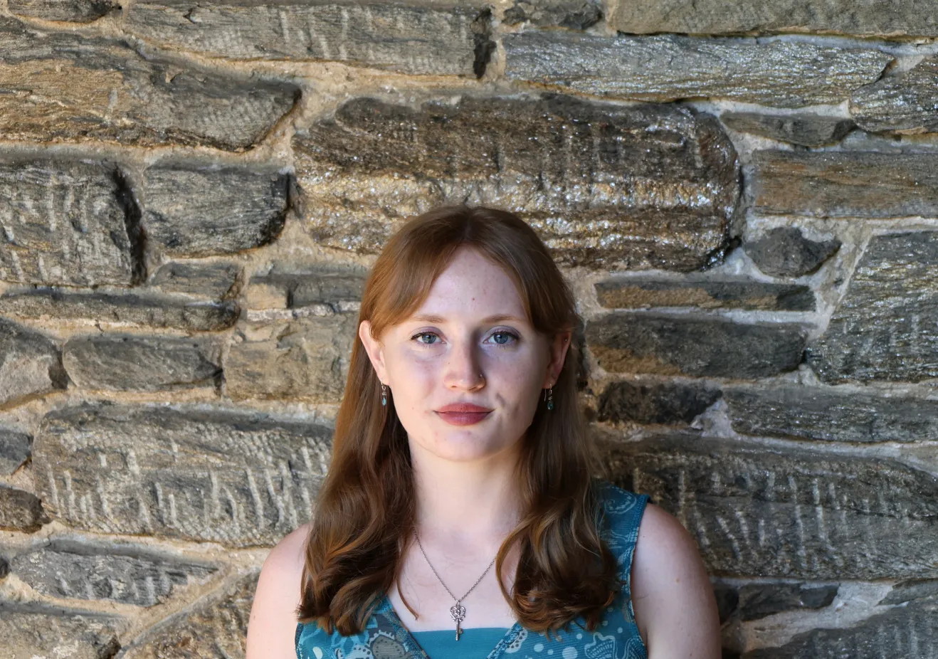 Lucy Gray Shamel poses in front of a stone wall