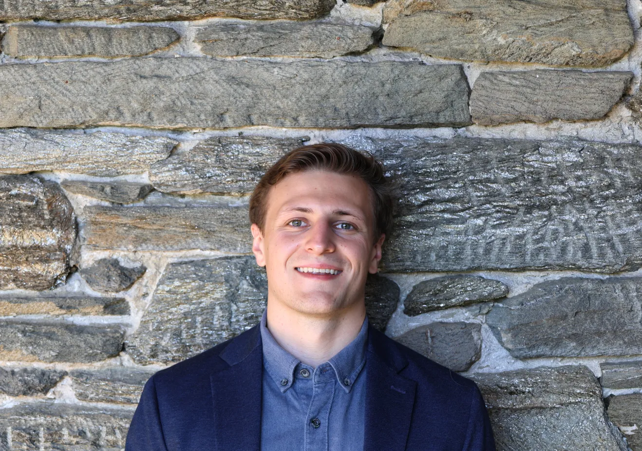 Brady Hill poses in front of a stone wall