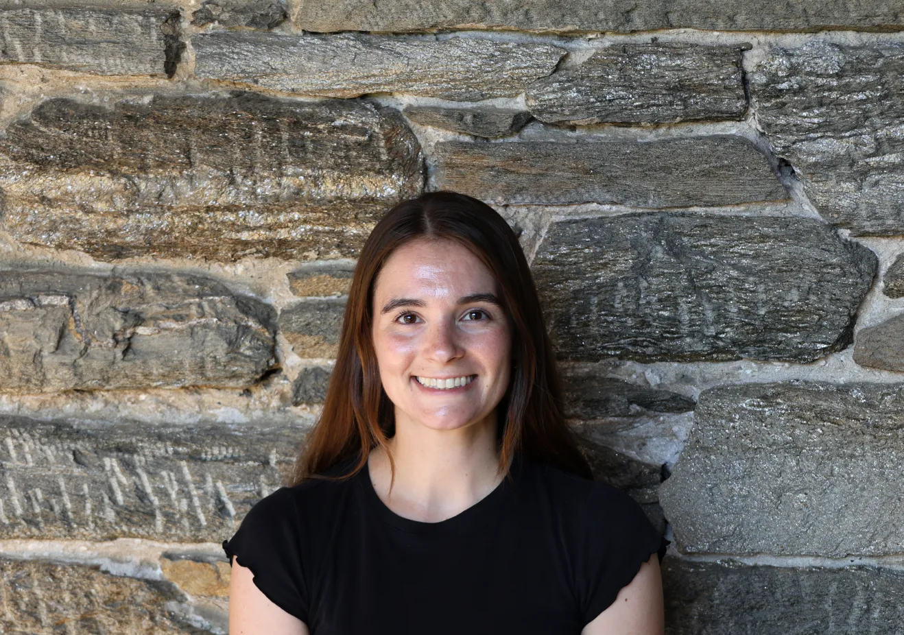 Kristen Lauritzen poses in front of a stone wall