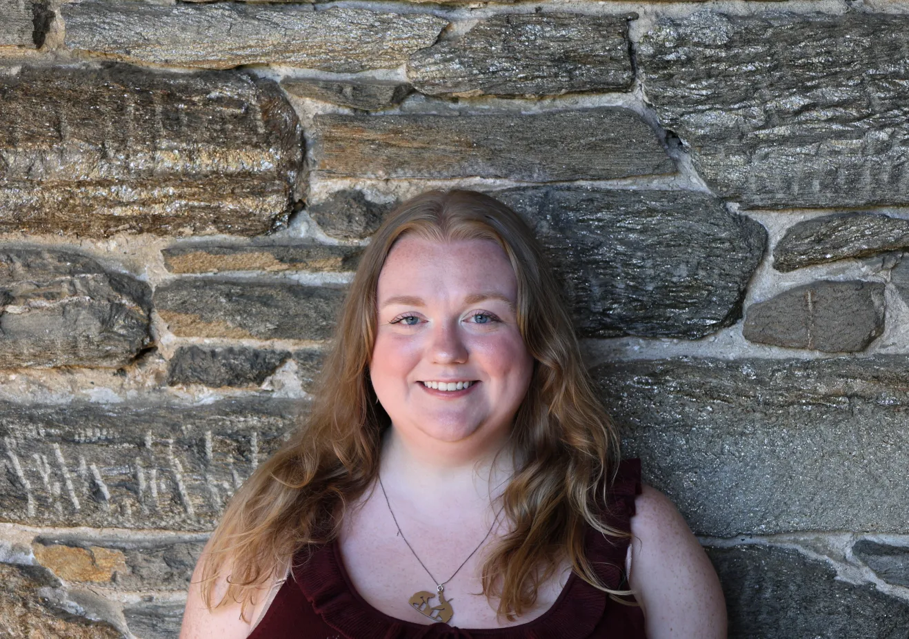 Megan Outtrim poses in front of a stone wall