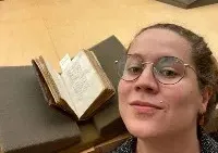 Kate Barnes takes a selfie next to a rare book.