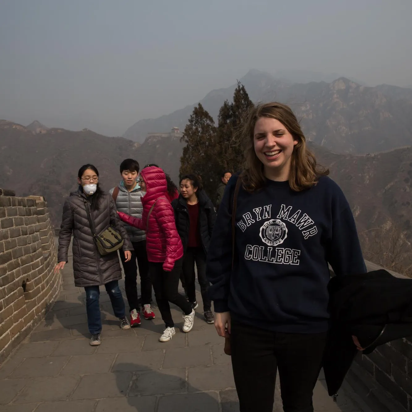 A group of students including a young woman with long light colored hair wearing a Bryn Mawr College sweatshirt walk a section of the Great Wall of China 