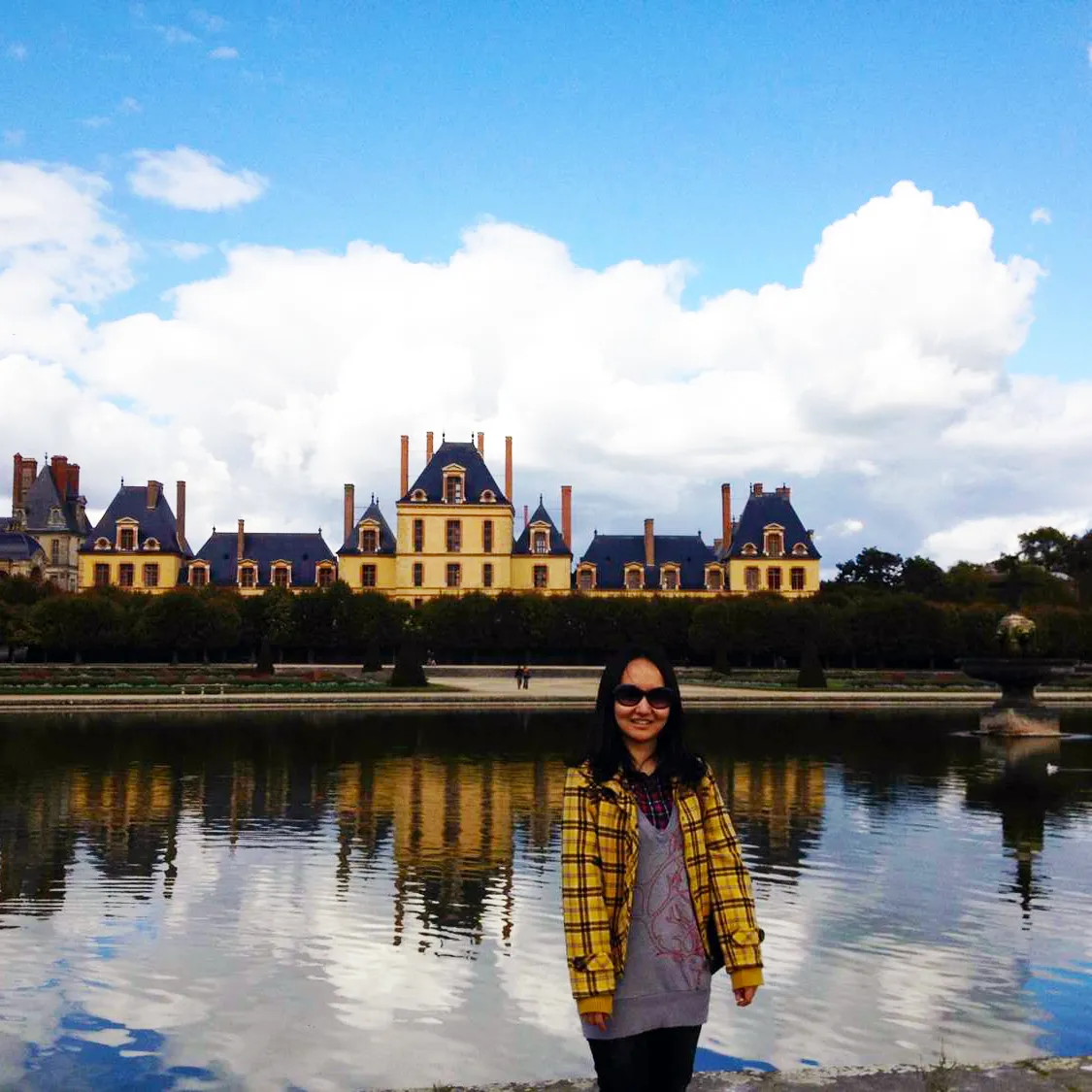 A Bryn Mawr College Francophone and French Studies student in a Lantern's Glow Plaid blazer in front of a Chateau in Paris, France