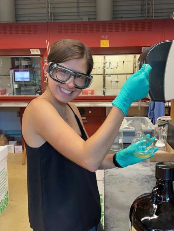 Yael Eiben smiling in the lab and filling a beaker