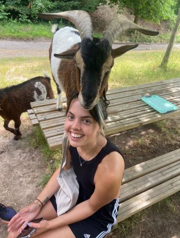 Clara Grosse sitting and smiling amongst goats. 