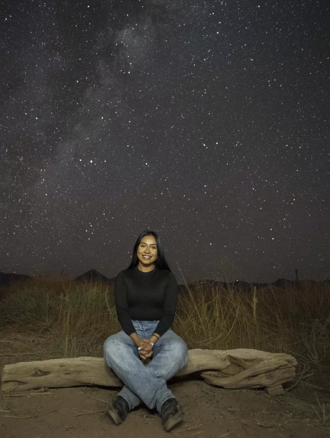 Nelid sitting under a sky full of stars. 