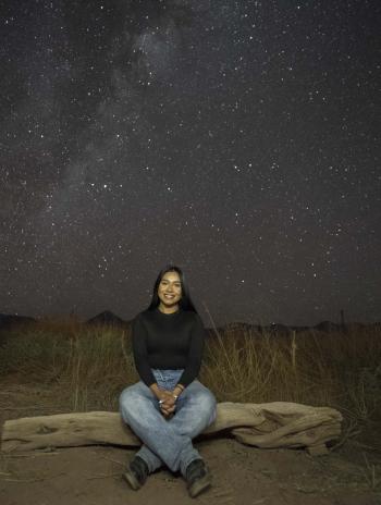 Nelid sitting under a sky full of stars. 