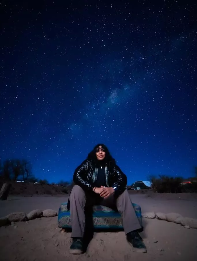 Jazmin sitting under a sky of stars. 