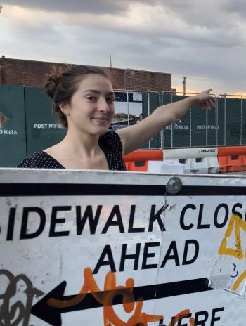 Emma Adelman in front of a sidewalk closed ahead sign. 