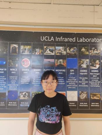 Xiyue Shen standing in front of a UCLA poster. 