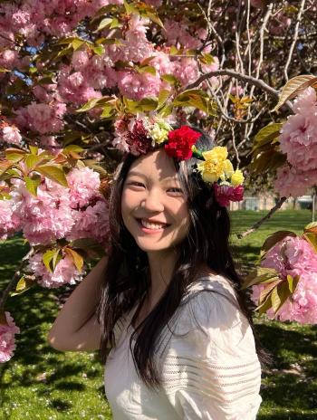 Sharon Liu in front of a cherry blossom tree. 