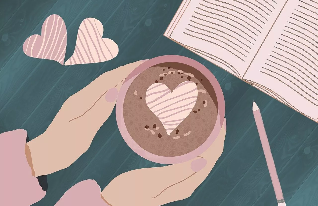 Hands holding a cup of cocoa and book