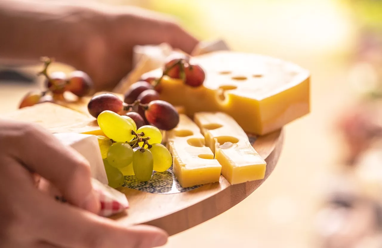 Hands holding a plate with cheese and grapes
