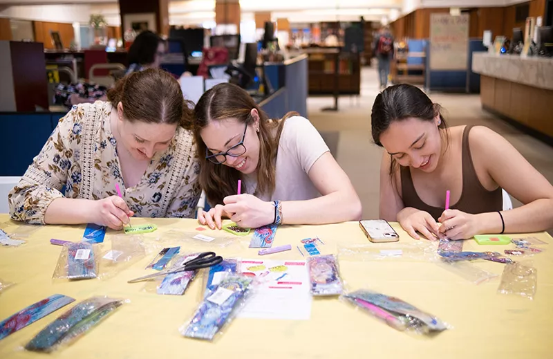 Students bedazzling bookmarks in library
