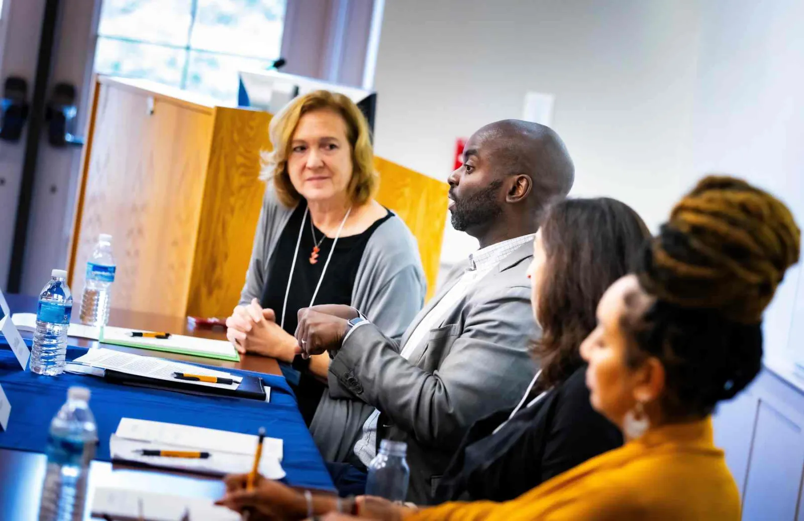 A panel of four people - one man and three women - sit at a table, in discussion