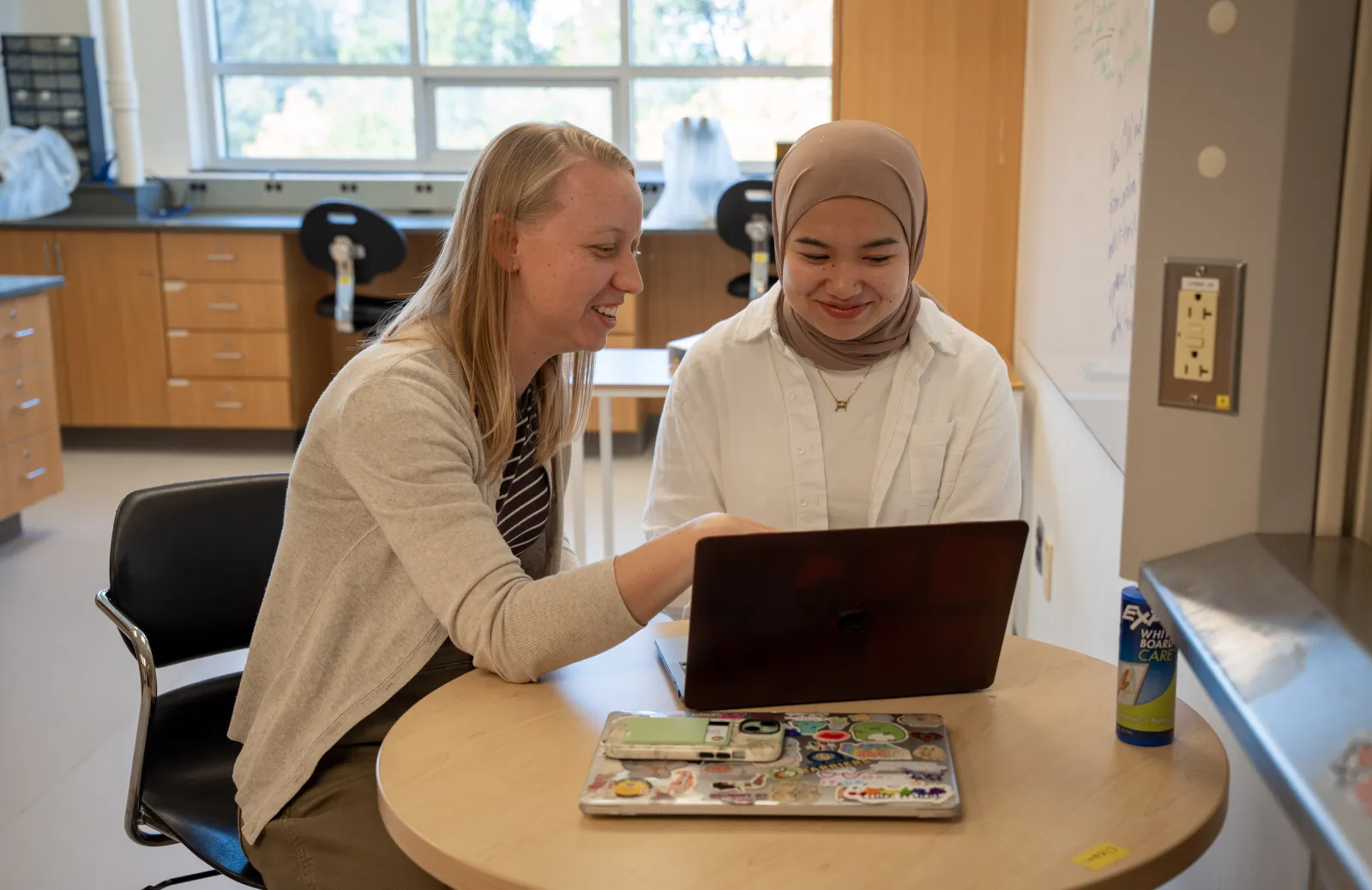Weber and students sitting at a computer and smiling