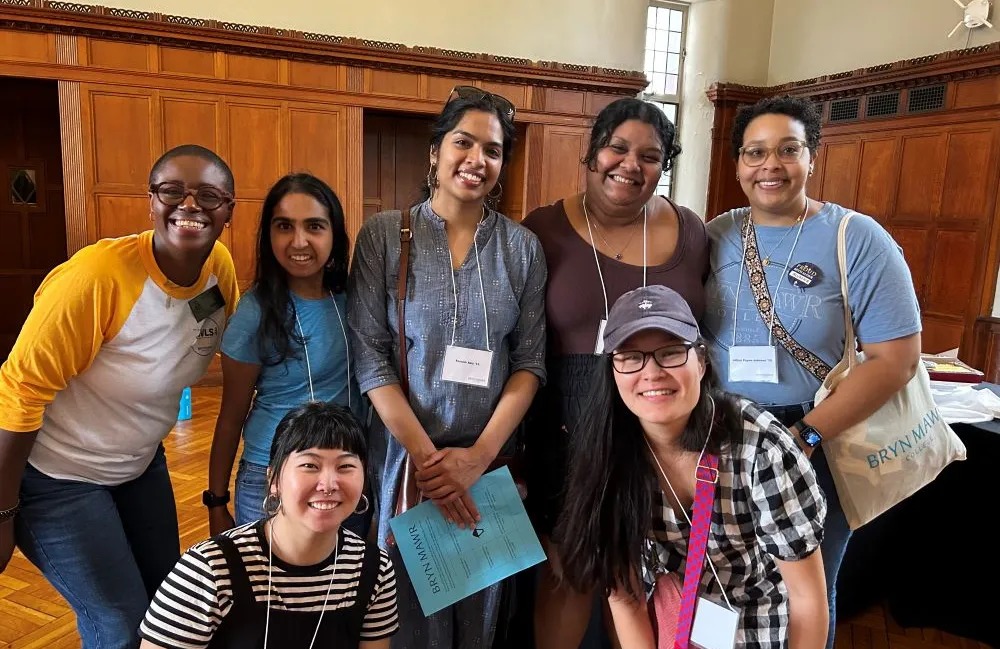 A group of alums stand together and smile at the camera.